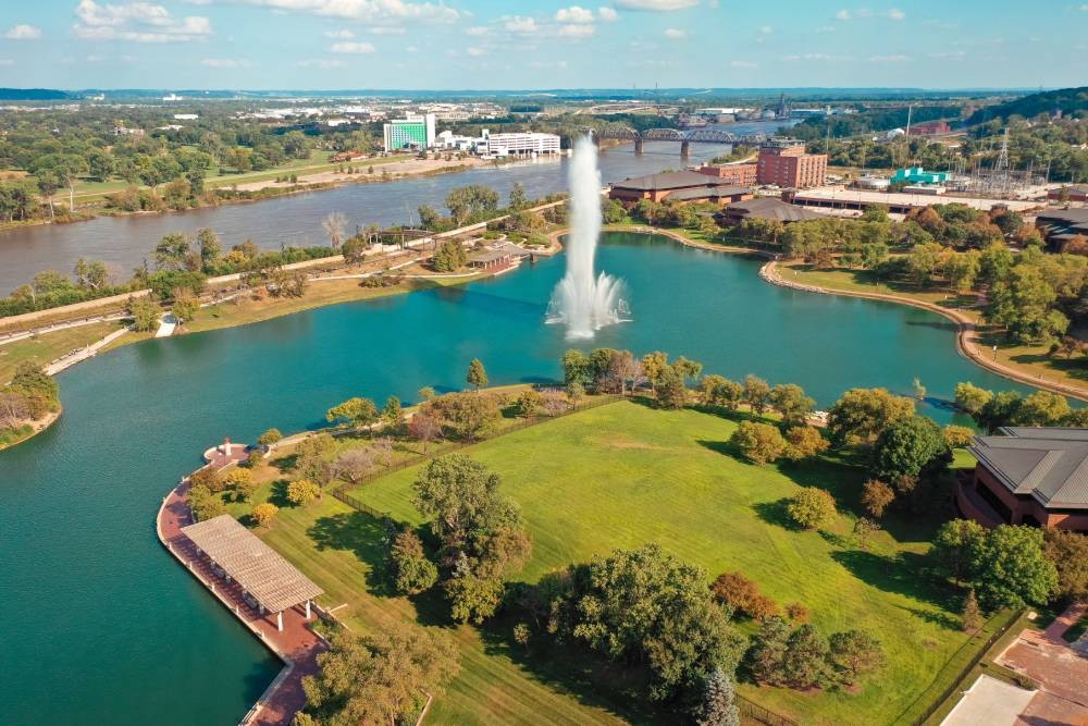 View of downtown Omaha, Nebraska with green land, trees, and blue water with a fountain spraying at Interior Re-Styling near Council Bluffs, Iowa (IA)