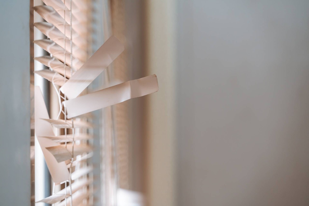 A window with broken blinds in need of a professional window treatment repair from Interior Re-Styling at Interior Re-Styling near Council Bluffs, IA