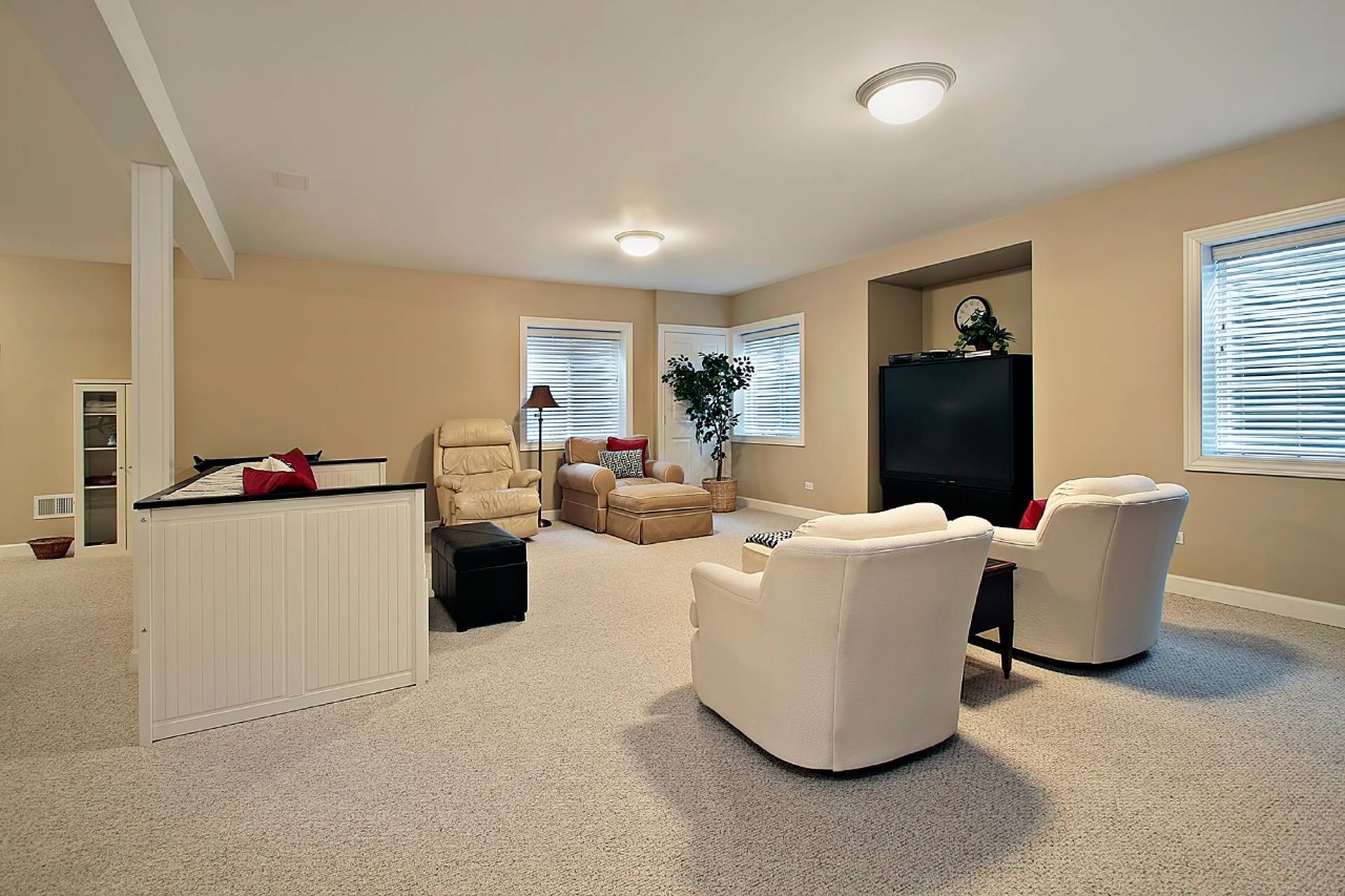 A finished basement with carpet, blinds for basement windows, and a designated seating area at Interior Re-Styling near Council Bluffs, IA